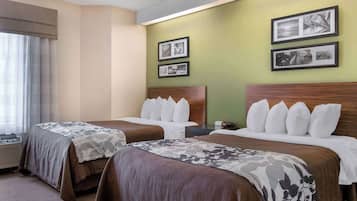 Una habitación de hotel con dos camas, un ventanal con cortinas y cuadros enmarcados en la pared.