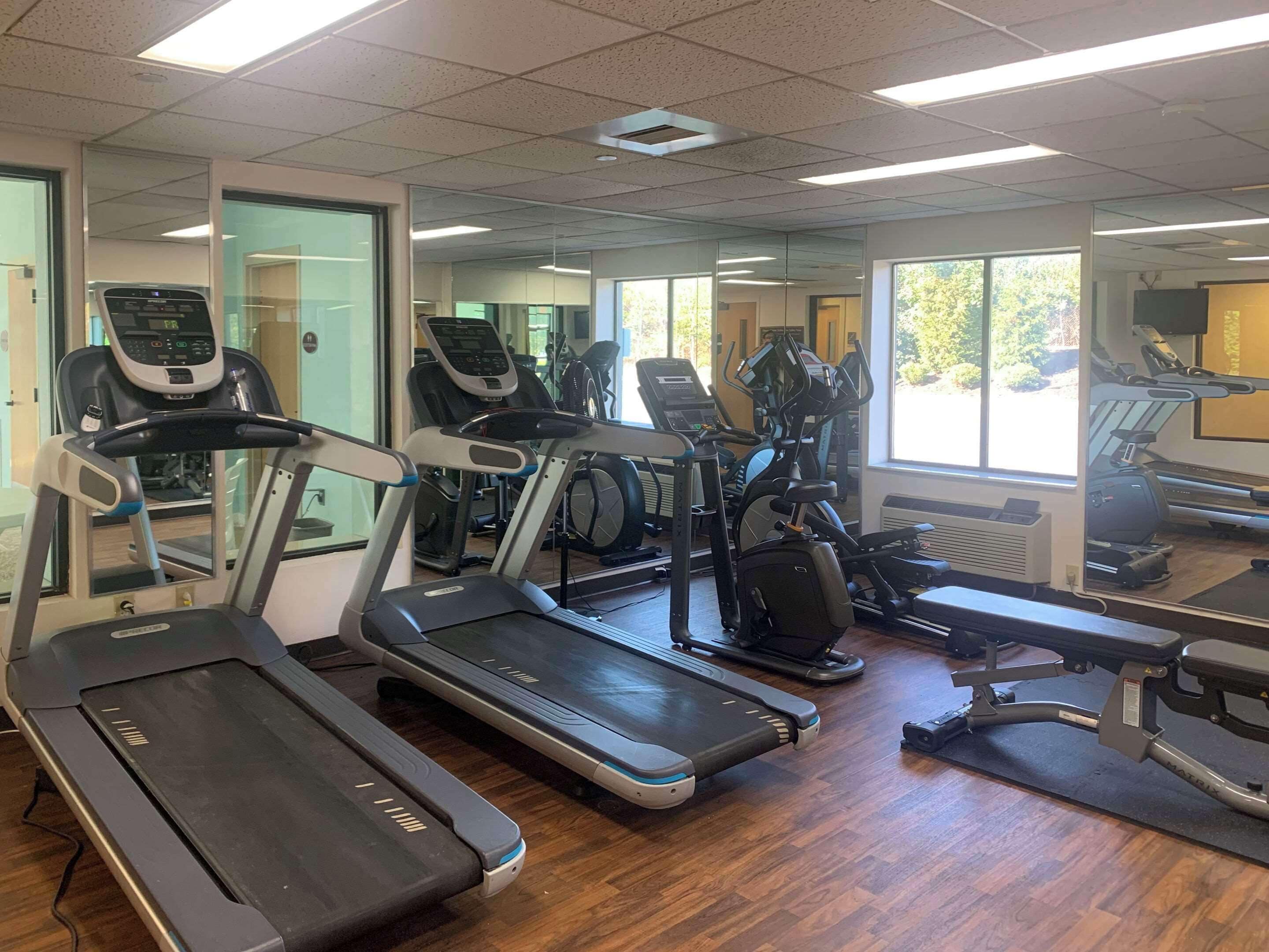 A gym with multiple treadmills, exercise bikes, and a mirrored wall.