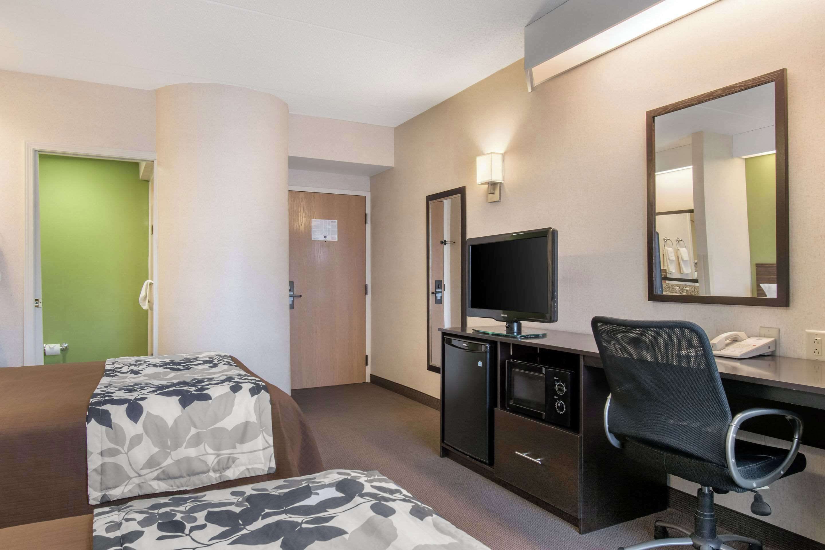 Habitació d'hotel amb dos llits, un escriptori amb ordinador, televisió i mirall.