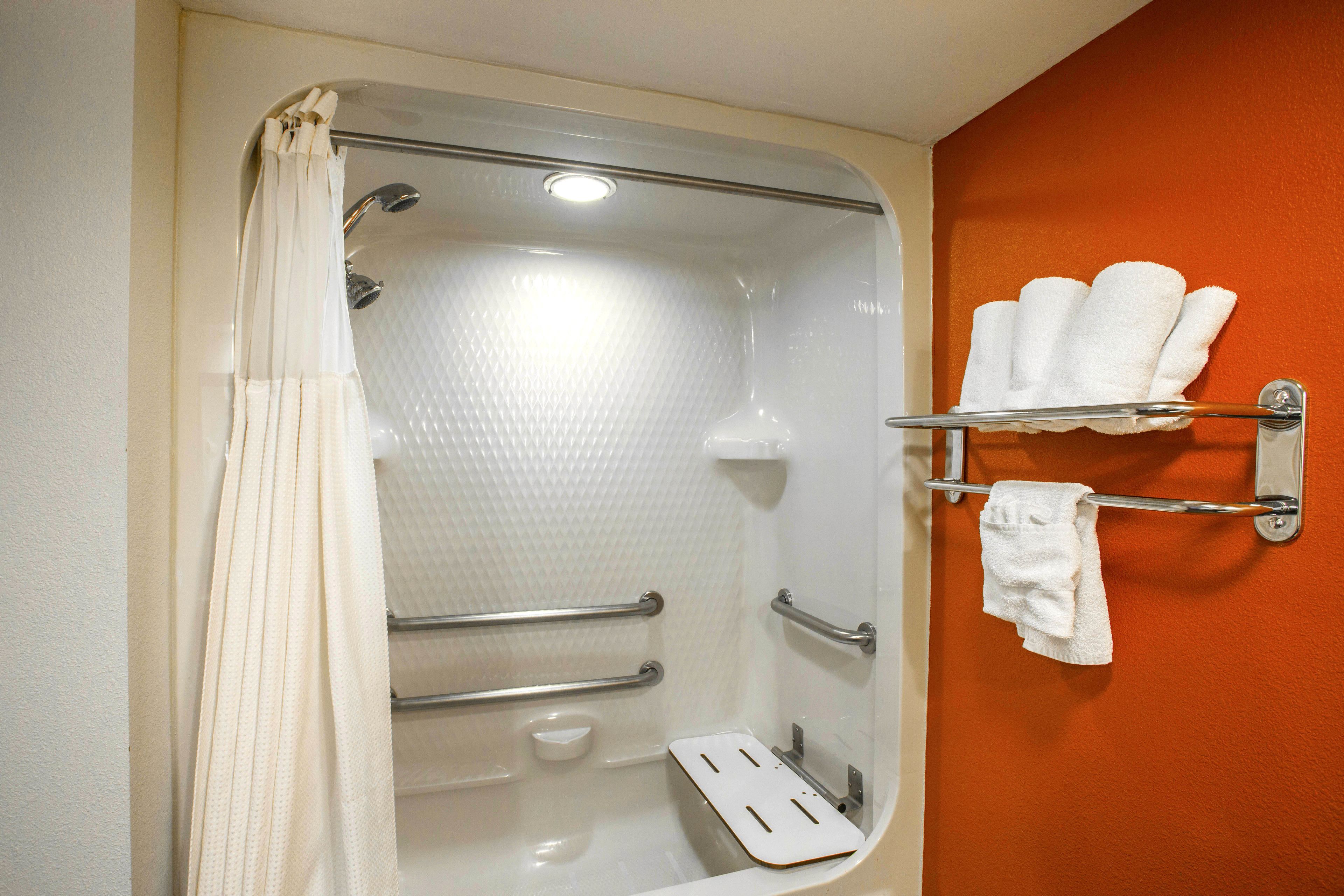 Une salle de bain équipée d’une douche, de barres d’appui, d’un porte-serviettes et d’un porte-savon.