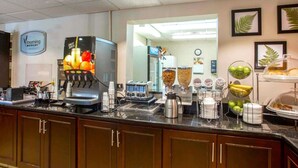 En frukostbar med en kaffemaskin, en juiceautomat och ett urval av olika matvaror.