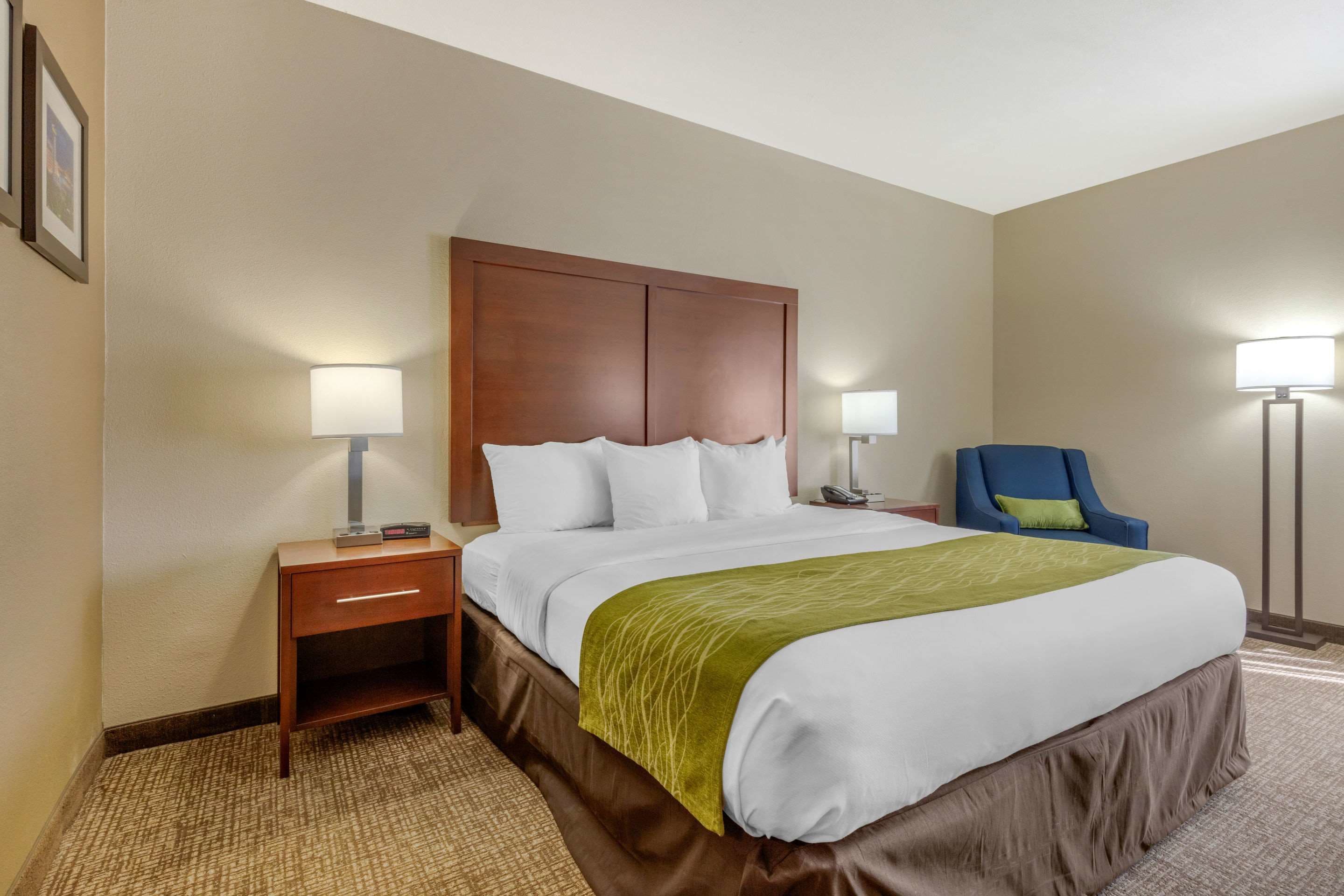 A hotel room with a large bed, two bedside tables, a chair, and a floor lamp.