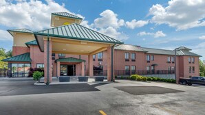 A hotel with a covered entrance, multiple floors, and a parking lot.