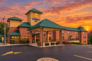Un hotel Comfort Inn con fachada de ladrillo, tejado verde y entrada cubierta.