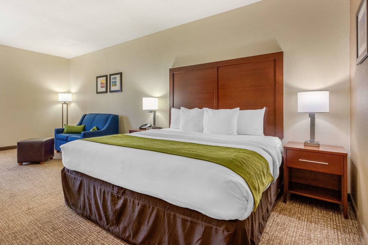 Une chambre d’hôtel avec un grand lit, un bureau, une chaise et deux lampes de chevet.