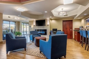 A hotel lobby with a fireplace, seating area, and a bar.