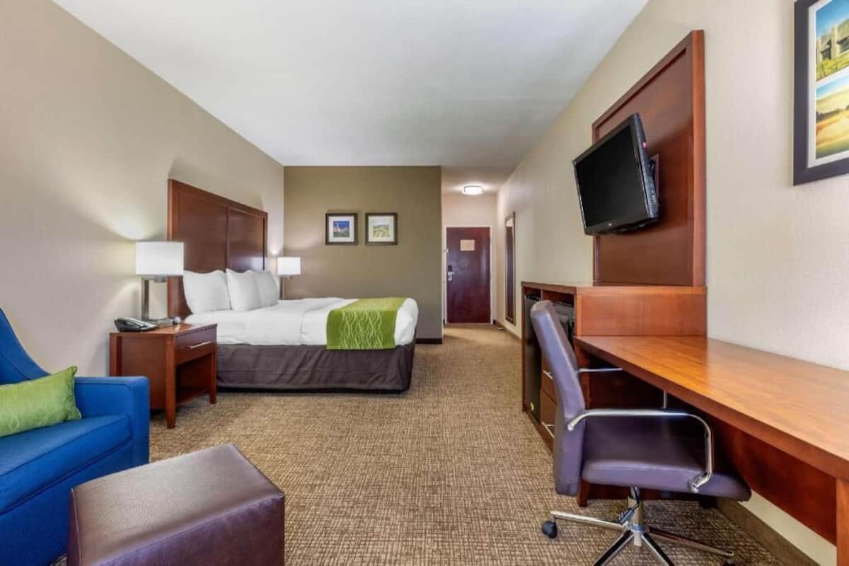 Une chambre d’hôtel avec un lit, un bureau, une chaise, une télévision et un canapé bleu.