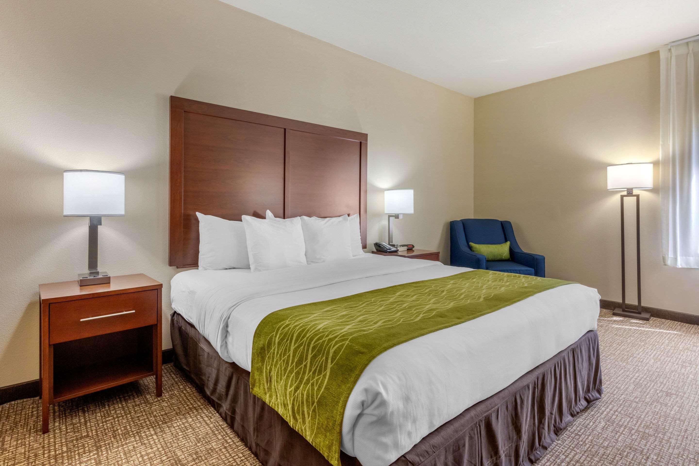 A hotel room with a large bed, two bedside tables, a chair, and a lamp.