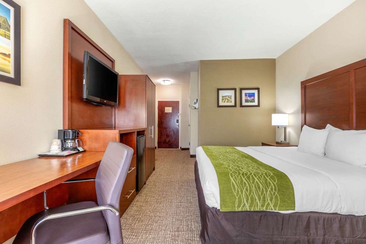 A hotel room with a bed, a desk with a chair, a television, and a coffee maker.