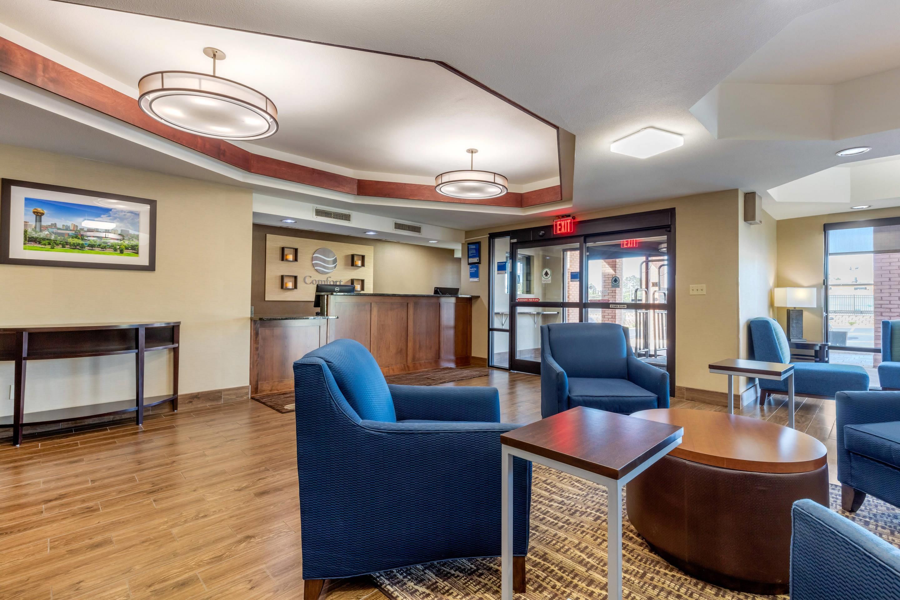 A hotel lobby with seating, a reception desk, and an exit sign.