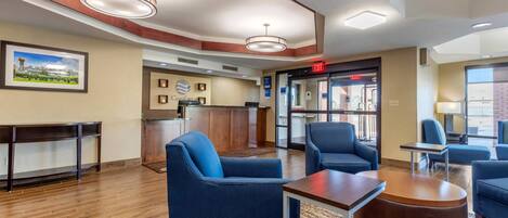 A hotel lobby with seating, a reception desk, and an exit sign.