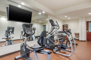 Un gimnasio con equipos de ejercicio variados, incluyendo cintas de correr y una máquina elíptica.