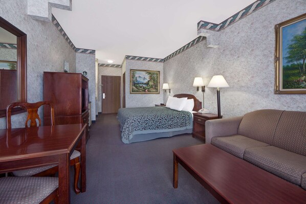A hotel room with a bed, a sofa, a desk, and a chair.