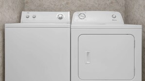 Dos lavadoras blancas de carga frontal, una al lado de la otra, frente a una pared con textura.