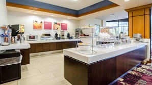 Ett modernt hotellkök med en central köksö, mikrovågsugn, kaffemaskiner och en buffé.