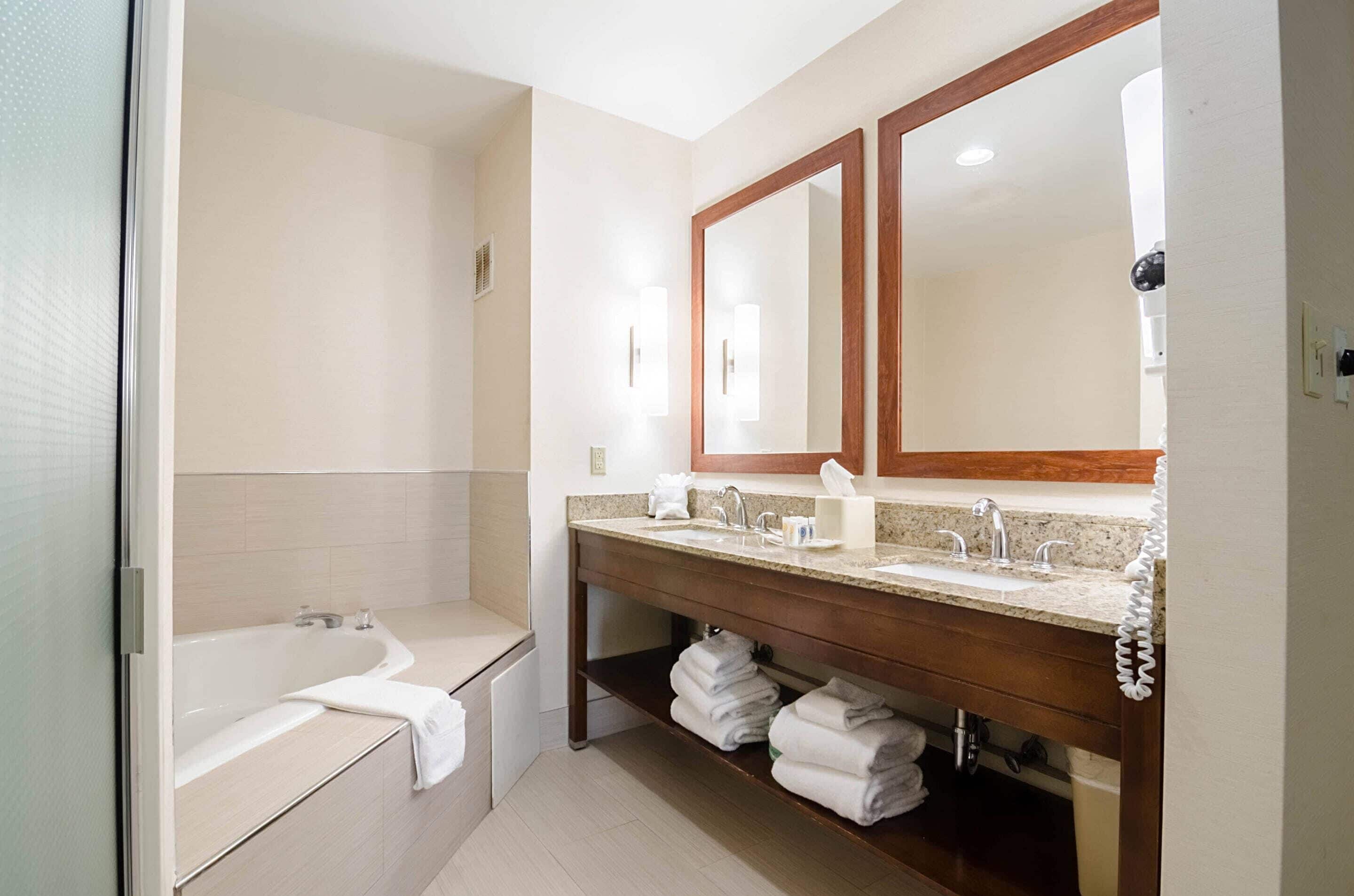 Un baño moderno con una bañera, un tocador con espejo y un estante con toallas.
