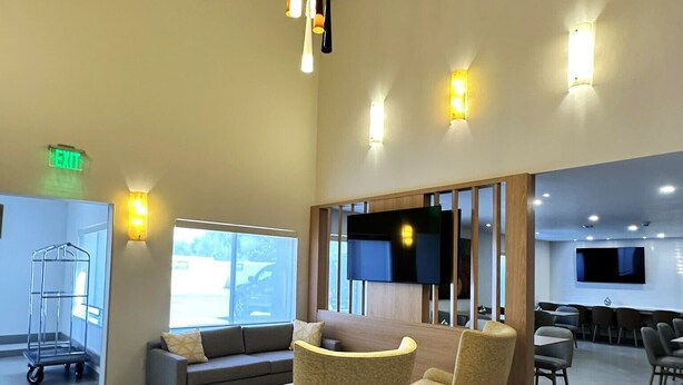 A spacious lobby with a sofa, chairs, a TV, and a cart. - Comfort Suites At Tucson Mall (Tucson)