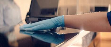 A person wearing a blue glove cleaning a reflective surface, possibly a counter or table.