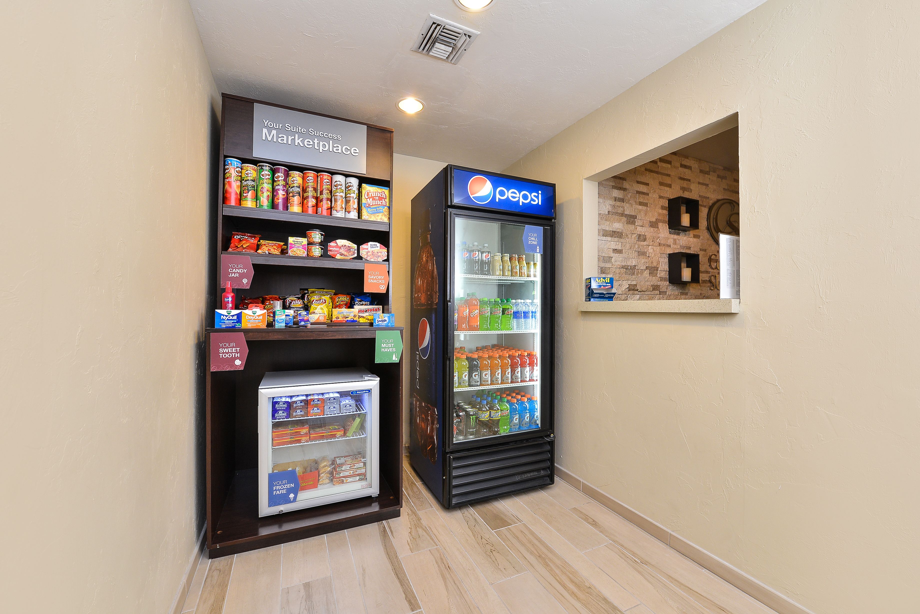 A vending machine area with a Pepsi refrigerator and a freezer stocked with snacks and beverages.