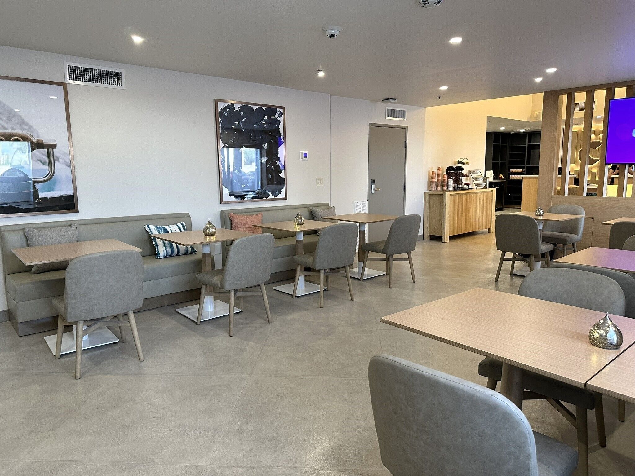 A modern cafe with seating arrangements, a counter, and a large abstract artwork on the wall.