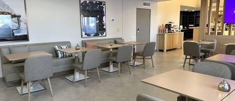 A modern cafe with seating arrangements, a counter, and a large abstract artwork on the wall.