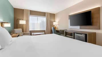 Habitación de hotel con una cama grande, un escritorio, un televisor de pantalla plana, un microondas y un refrigerador pequeño.