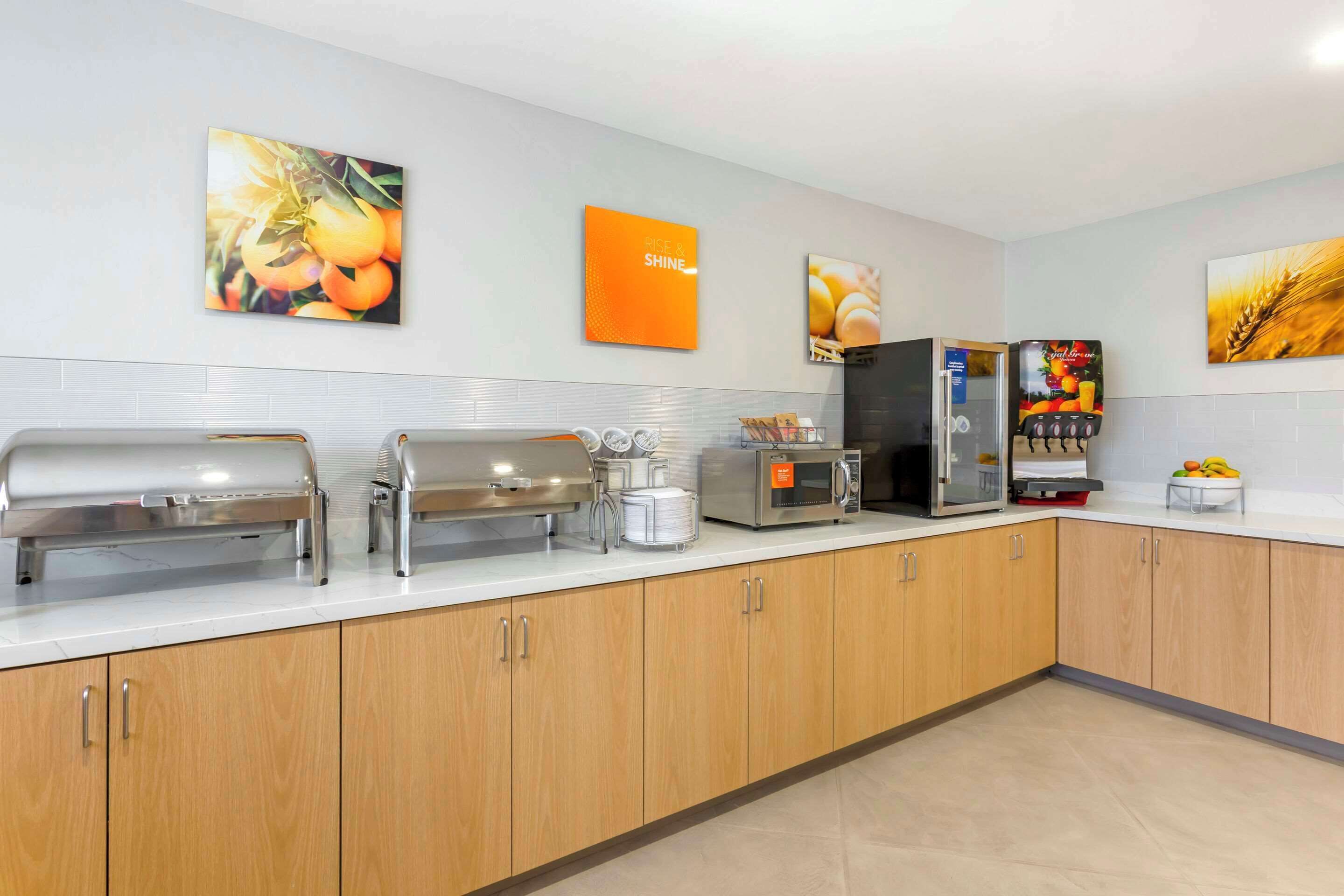 A modern kitchen with a buffet setup, including a grill, microwave, and beverage dispenser.