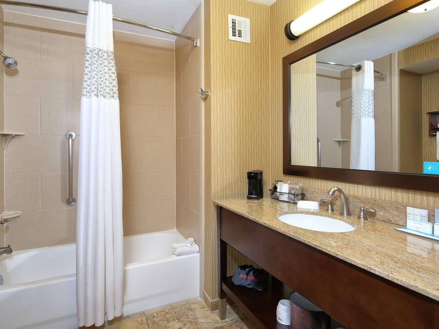 A bathroom with a bathtub, shower, and vanity with a sink and mirror.