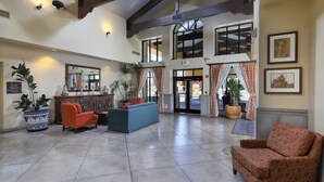 A spacious lobby with a high ceiling, large windows, and a central seating area with a sofa and armchairs. - Hampton Inn & Suites Tucson-Mall (Tucson)