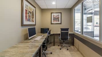 A conference room with a marble table, two monitors, chairs, and framed artwork on the walls.