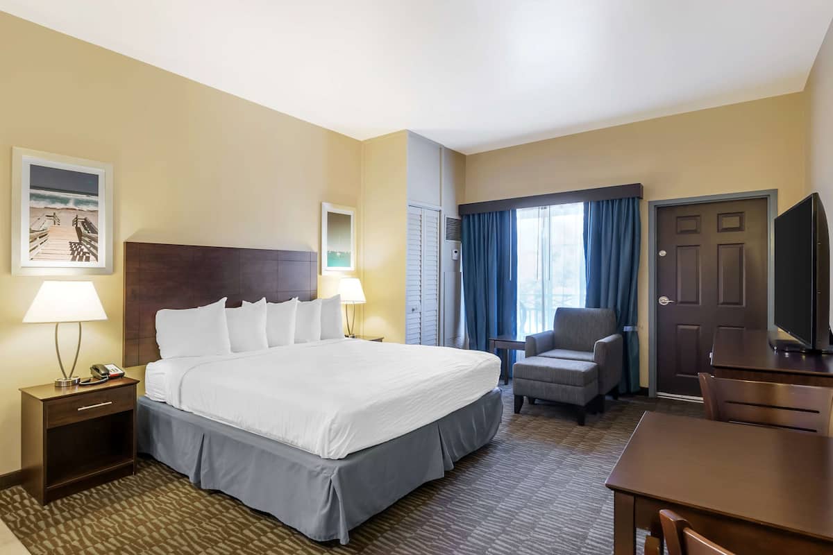 Une chambre d’hôtel avec un grand lit, des tables de chevet avec des lampes, une chaise, un bureau et un téléviseur.