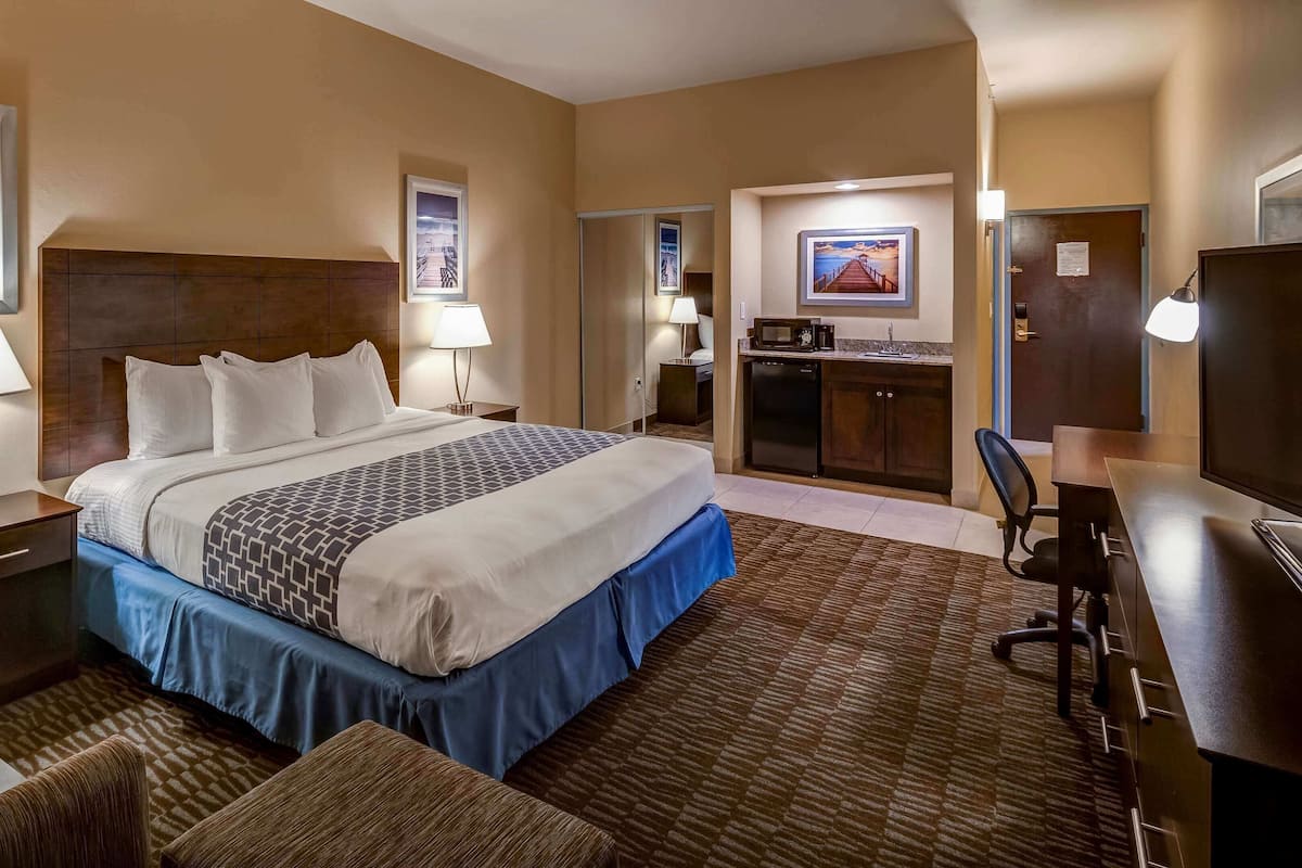 Une chambre d’hôtel équipée d’un lit, d’un bureau, d’une chaise et d’une kitchenette.