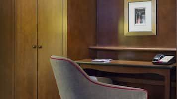 A wooden desk with a telephone and a framed picture on the wall.