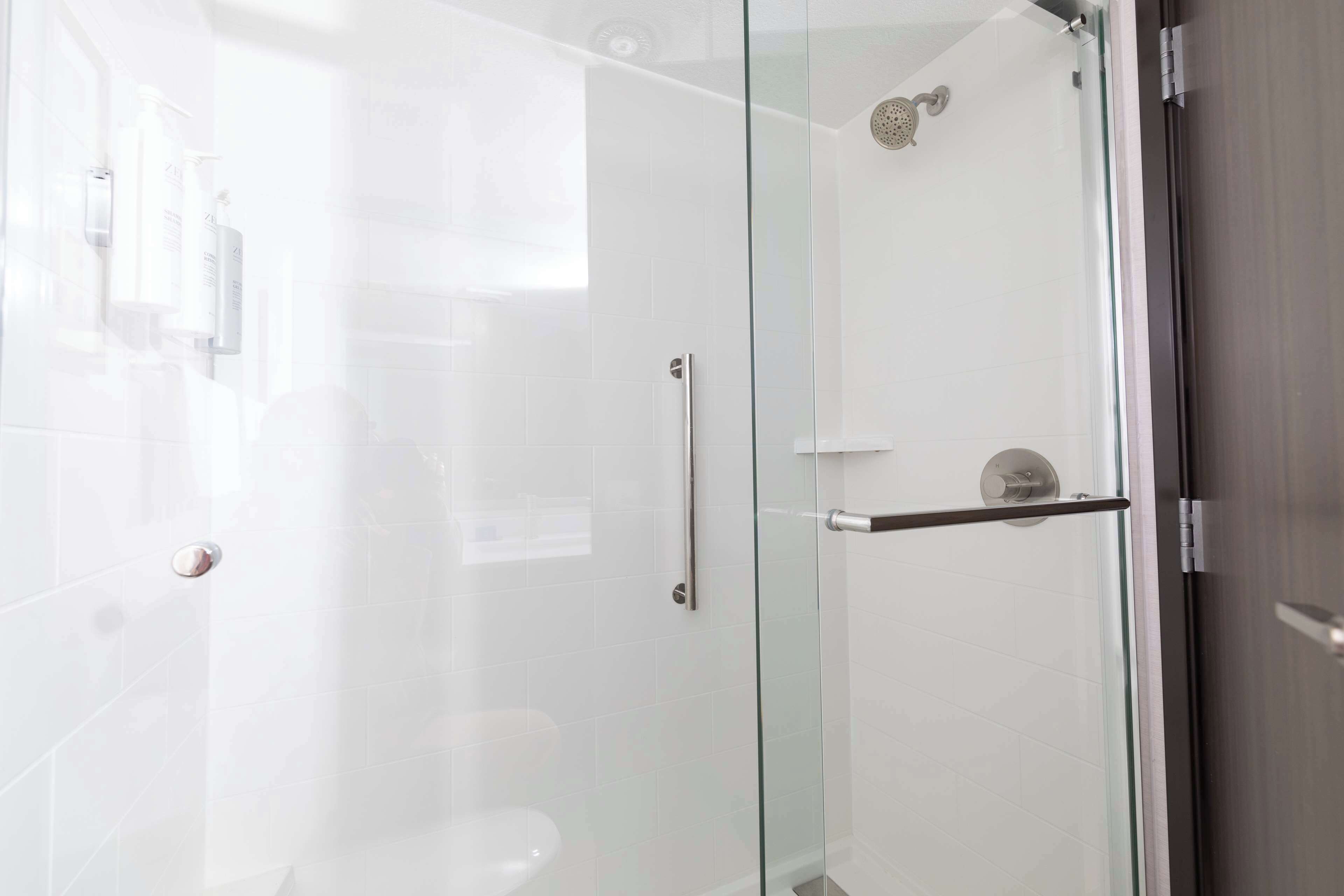 A modern bathroom with a glass shower enclosure, a toilet, and a glass door.