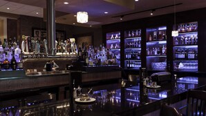 Eine Bar mit einer polierten Theke, einer Auswahl an Flaschen und Gläsern und einer ansprechenden Beleuchtung.