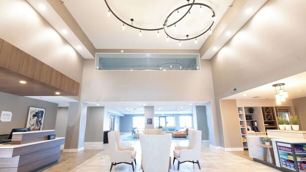 Eine geräumige Lobby mit einer Rezeption, einer Sitzecke und einer im Hintergrund sichtbaren Küche.