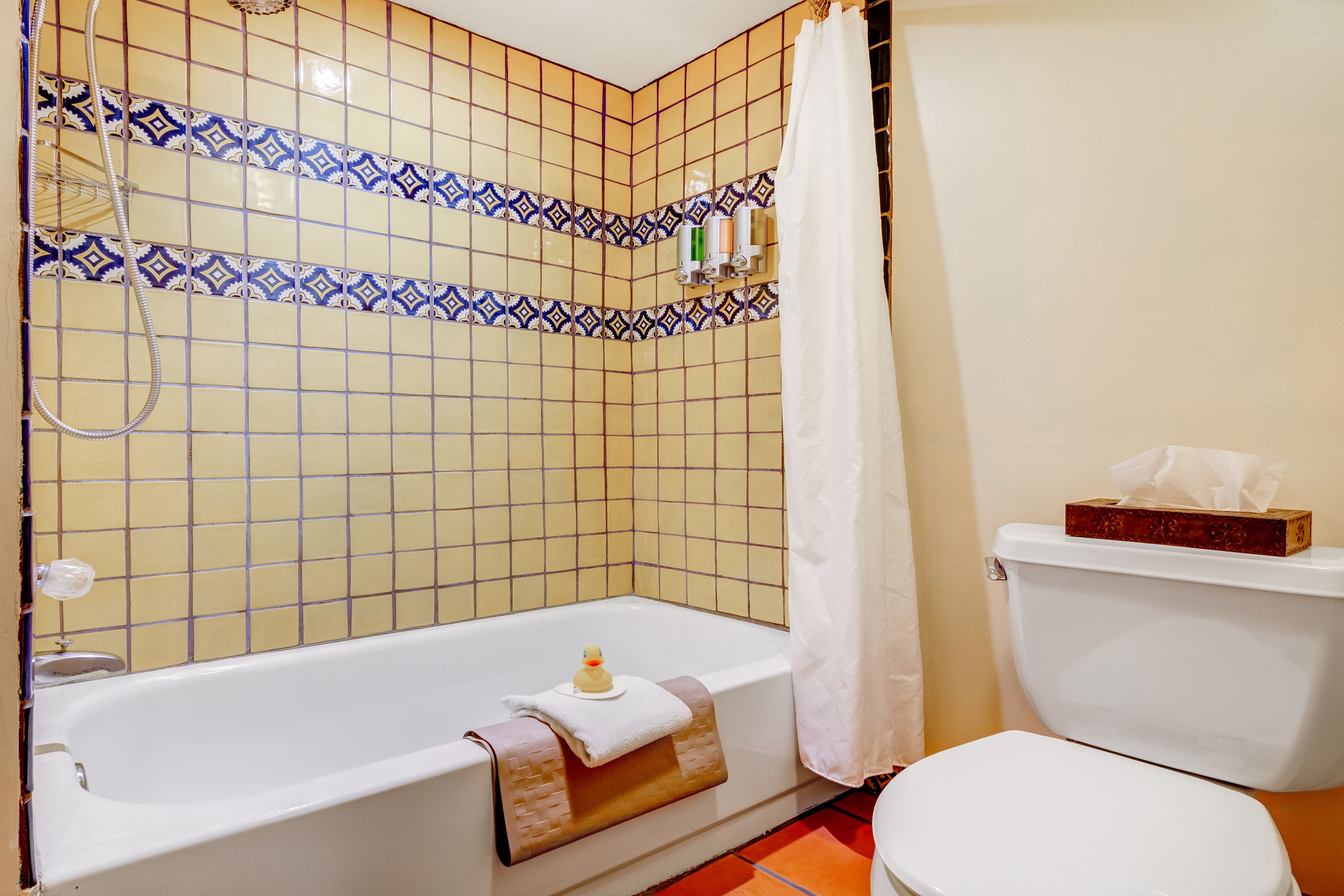 A bathroom with a bathtub, toilet, and shower curtain.