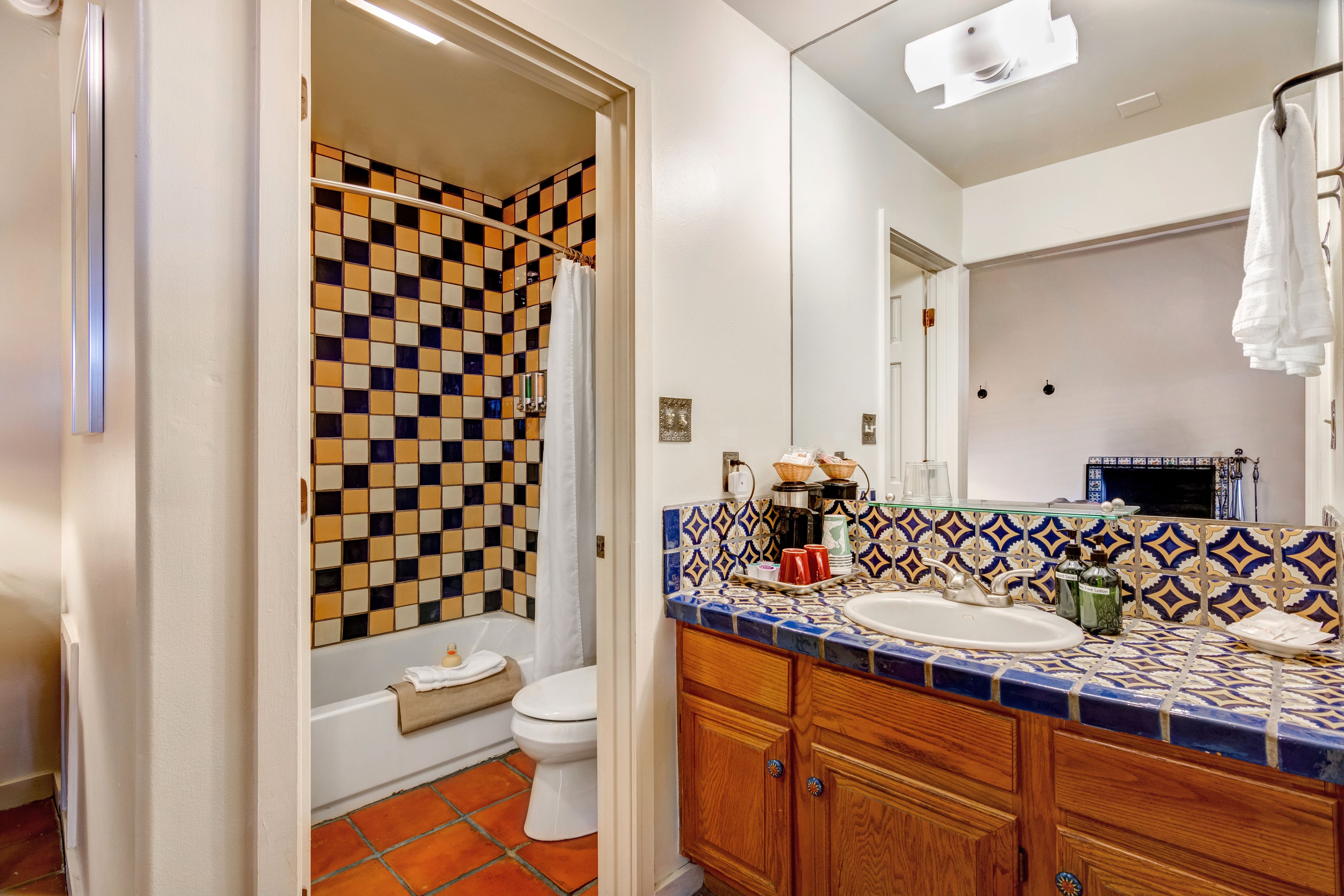 A bathroom with a checkered shower wall, a white toilet, and a sink with a patterned tile backsplash.