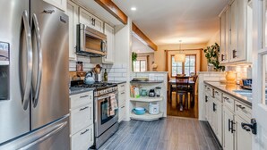 A modern kitchen with stainless steel appliances, white cabinetry, and a wooden ceiling beam. - Santa Fe Motel & Inn (Santa Fe)