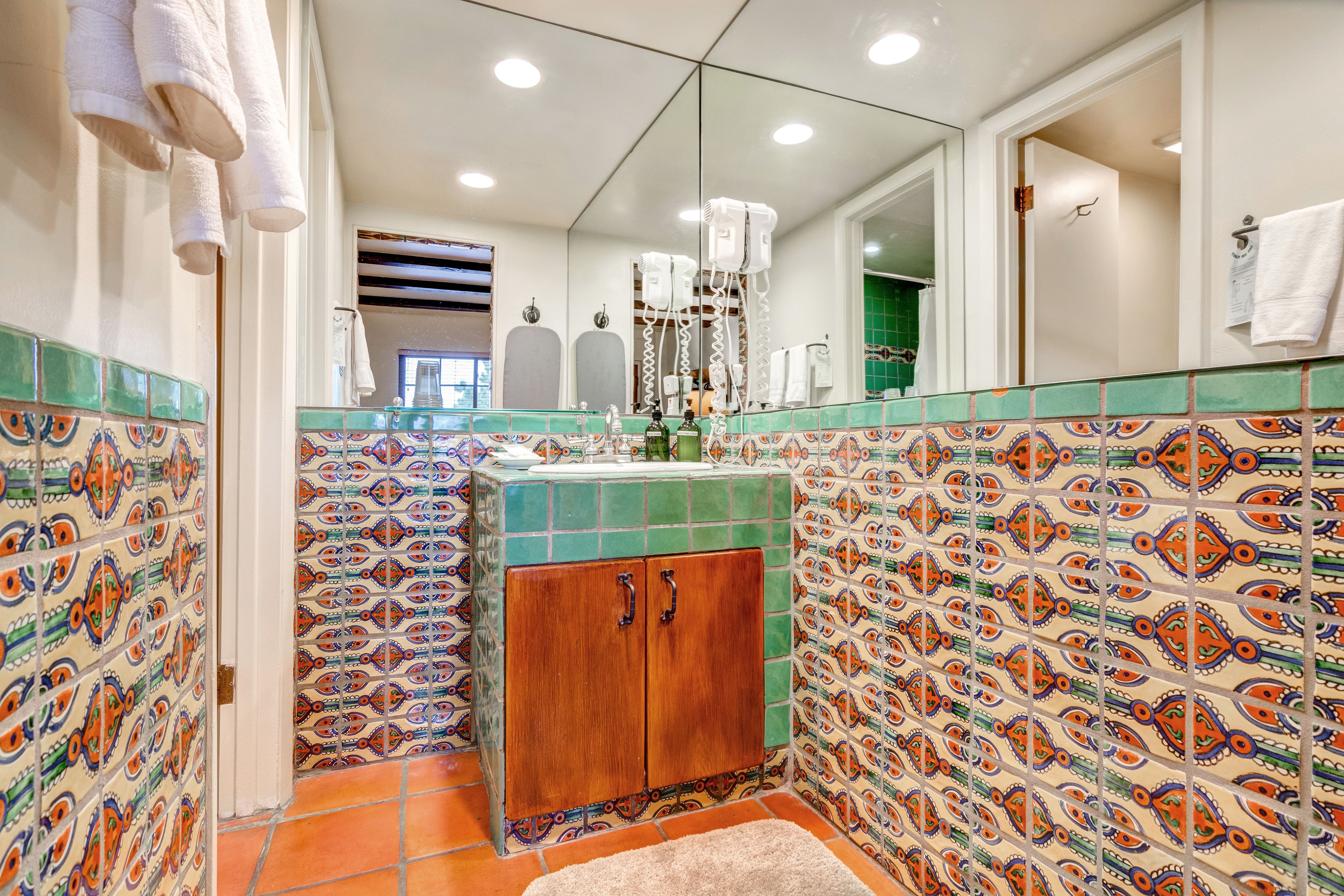 A bathroom with patterned tiles, a wooden cabinet, and a mirror.