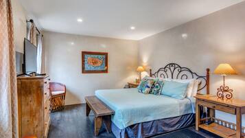 A bedroom with a bed, bedside tables, a bench, a dresser, and a television.