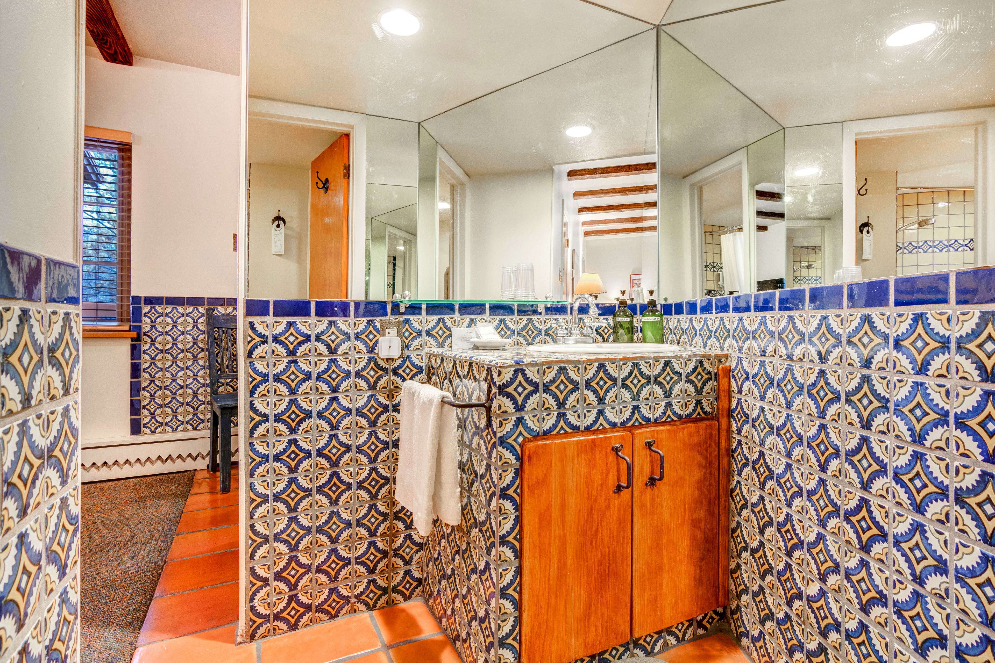 A bathroom with patterned tiles, a wooden cabinet, and a mirror.