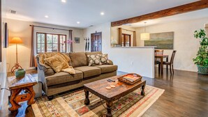 A cozy living room with a sofa, coffee table, and a dining area with chairs and a table. - Santa Fe Motel & Inn (Santa Fe)