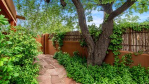 A stone pathway leading to a wooden gate, surrounded by lush greenery and a large tree. - Santa Fe Motel & Inn (Santa Fe)