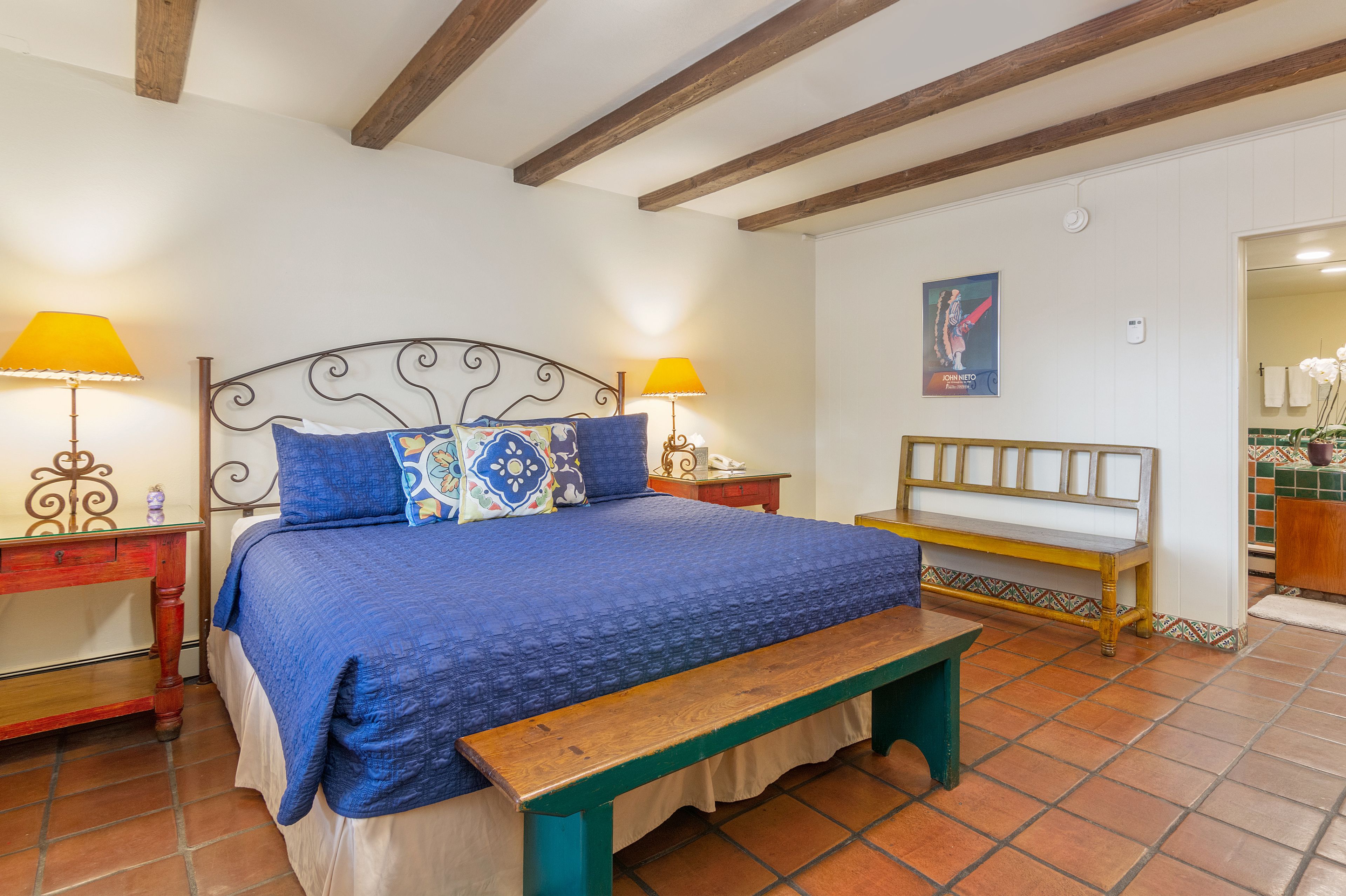 Een slaapkamer met een groot bed, twee nachtkastjes, een bankje en een houten hoofdbord.