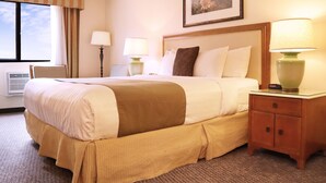 A hotel room with a large bed, two bedside tables with lamps, a framed picture on the wall, and a window with curtains. - Cities Of Gold Casino (Santa Fe)