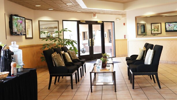 A reception area with black chairs, a coffee station, and a large mirror. - Cities Of Gold Casino (Santa Fe)