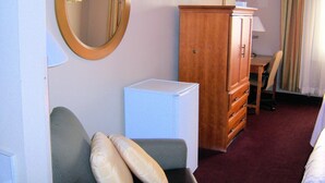 A hotel room with a bed, a desk, a dresser, a mirror, and a refrigerator. - Cities Of Gold Casino (Santa Fe)
