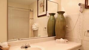 A bathroom with a sink, two green vases, a hair dryer, and a framed picture on the wall. - Cities Of Gold Casino (Santa Fe)