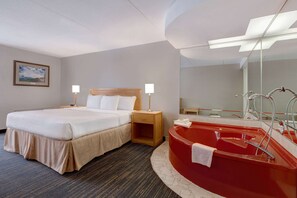 Ein Hotelzimmer mit einem Bett, Nachttischlampen, einer roten Badewanne und einem großen Spiegel.